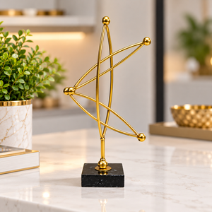 Gold abstract metal sculpture with curved lines and a black base on a console