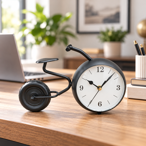 Black bicycle-shaped metal table clock with a white dial – bicycle table clock on a desk beside a laptop